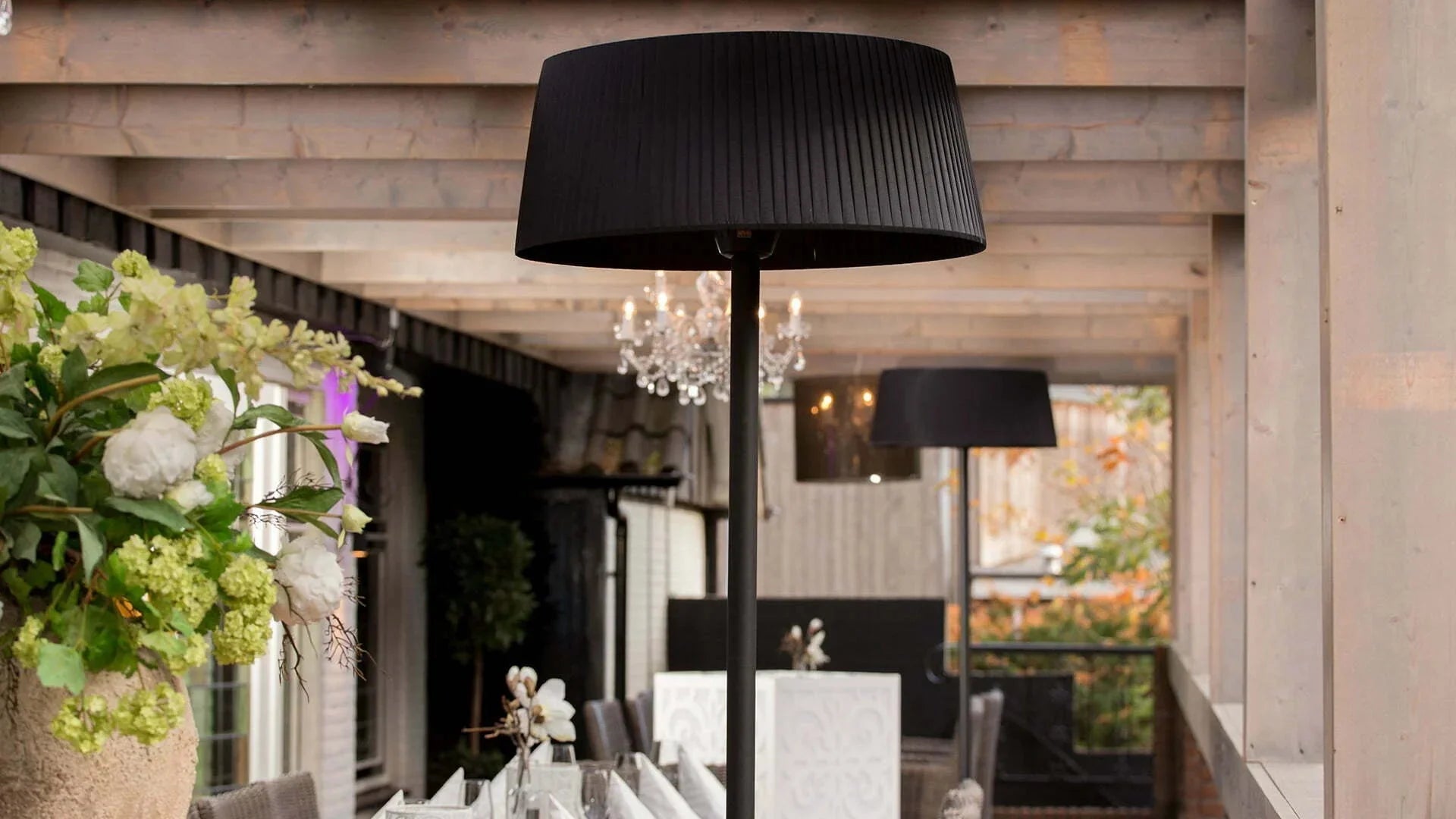 Artix Bright staande heater van Sunred onder een gezellige overkapping in de tuin