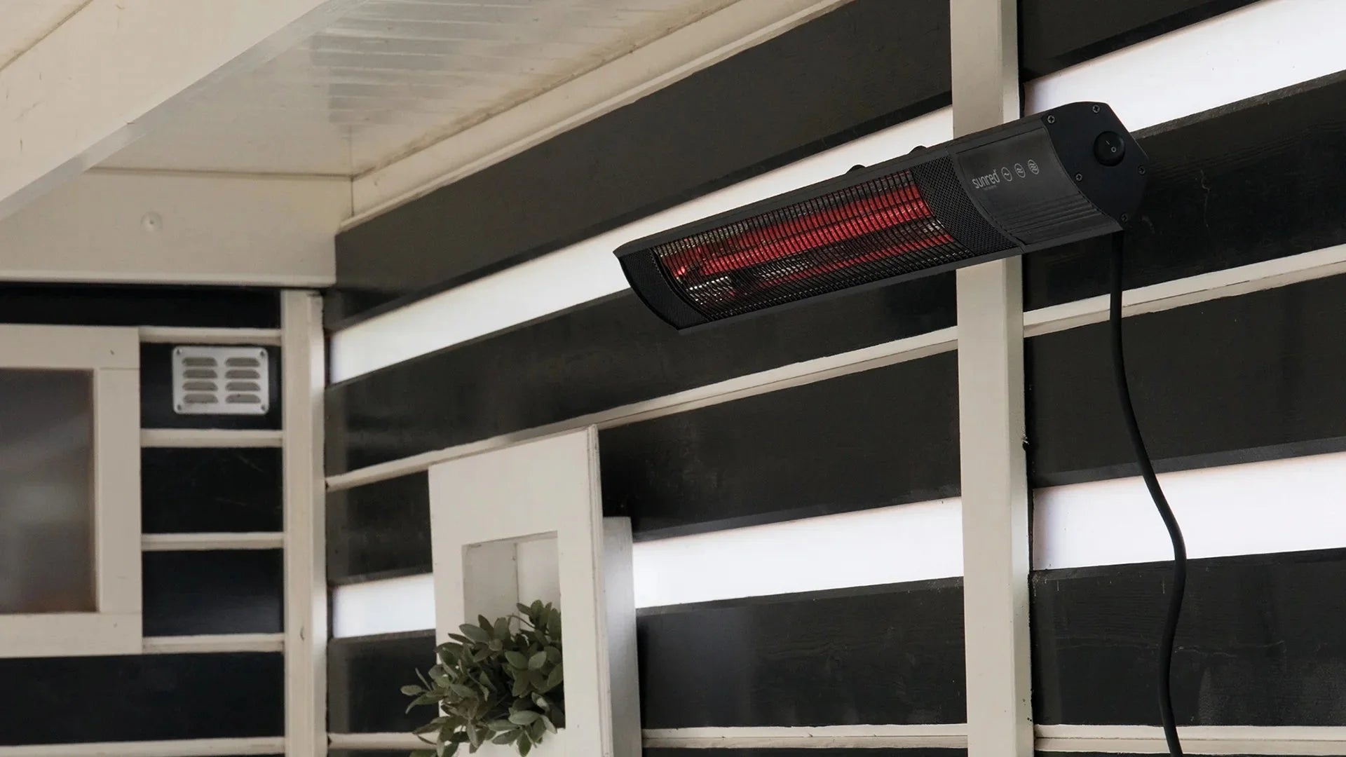 Sunred zwarte terrasverwarmer voor aan de wand met infrarood licht in gezellige tuin