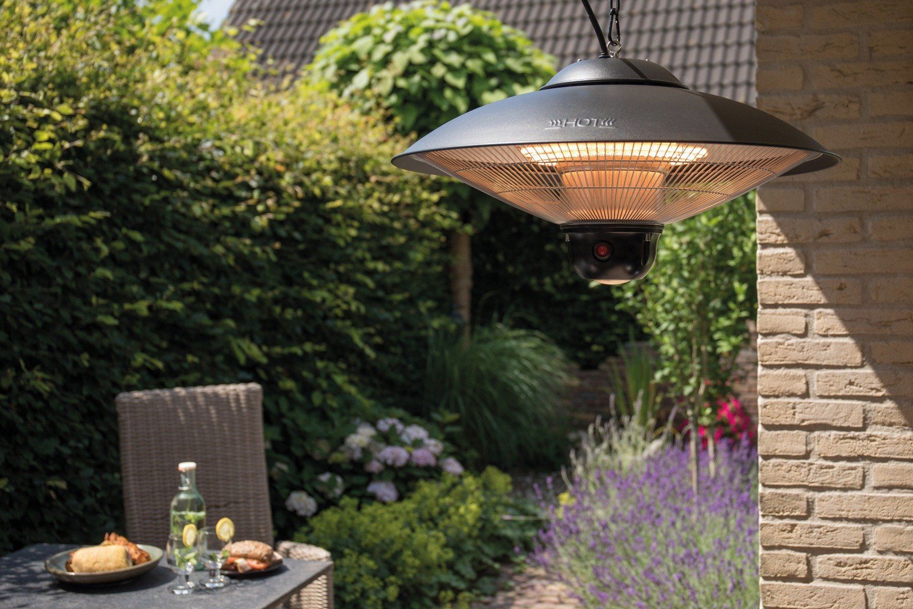 sfeervolle tuin met een zwarte hangende Sunred Sirius terrasverwarmer met 2100 Watt